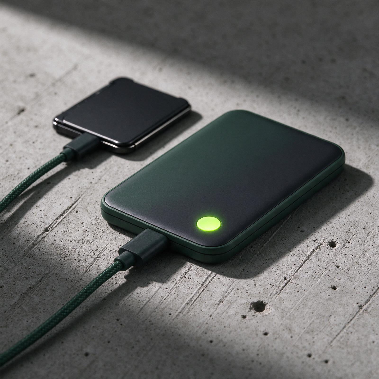 Macro view of a dark green hardware wallet and its glowing confirmation button
